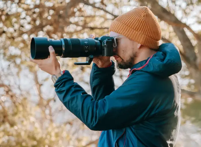 Photo of a man holding the OM-3 with the 100-400mm II